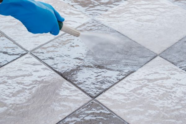a person using a pressure washer to clean the outdoor tiles