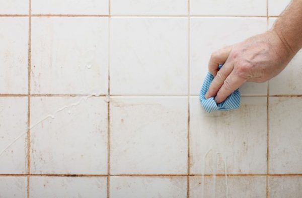 a man cleaning off the tile grout with soap and a cloth