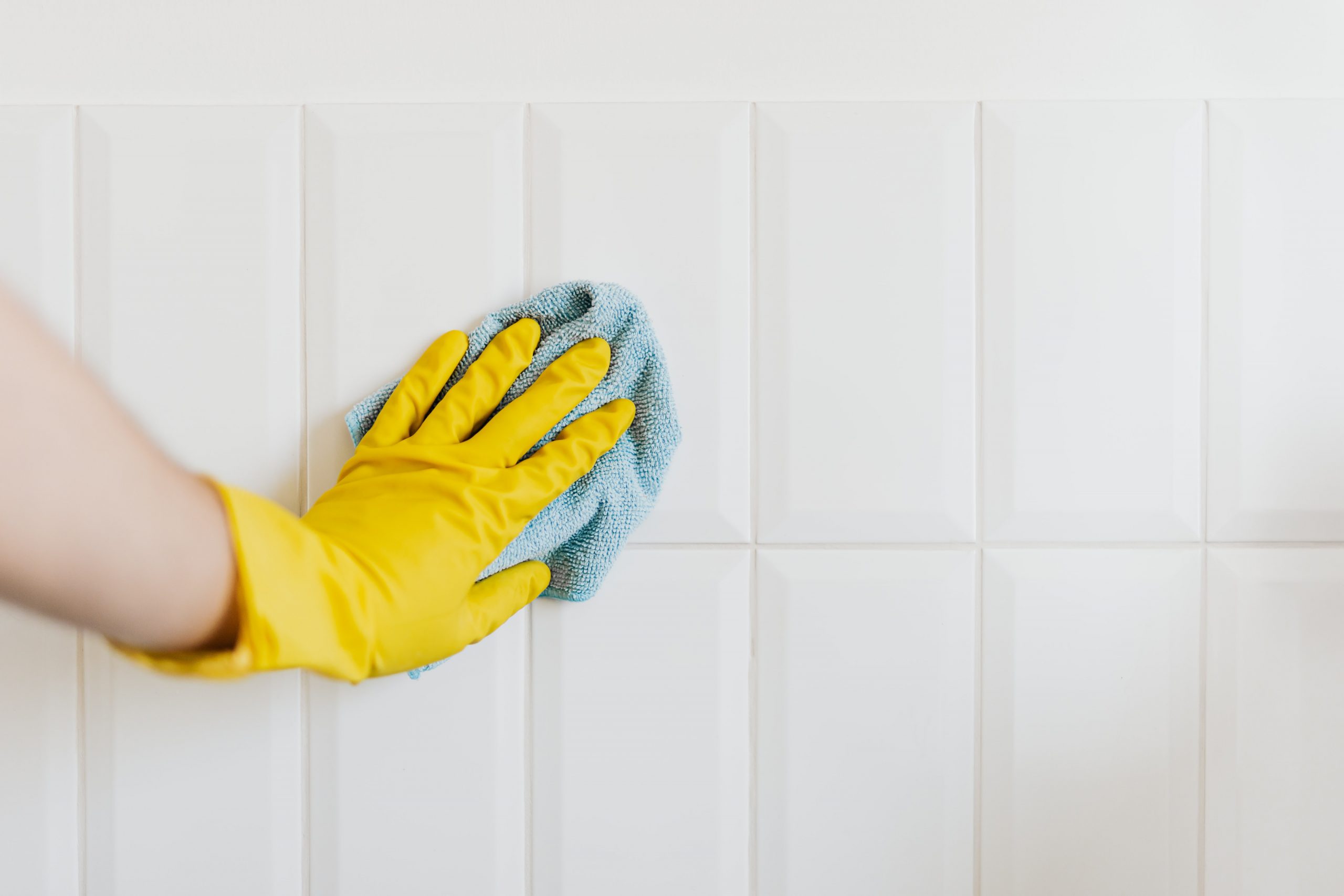 cleaning white wall with cloth and gloves