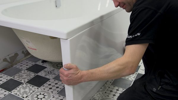 A man in a black shirt replacing bath panels