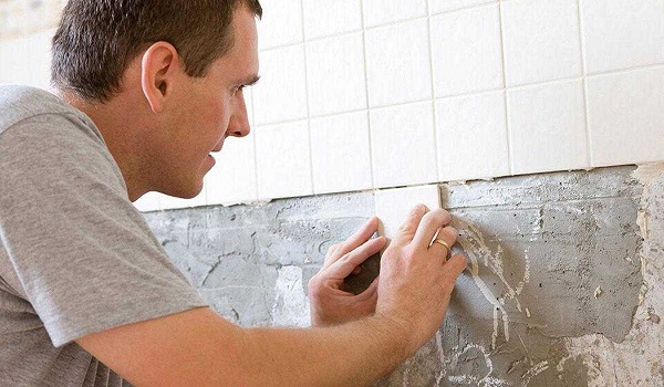 A man installing tiles on the kitchen wall