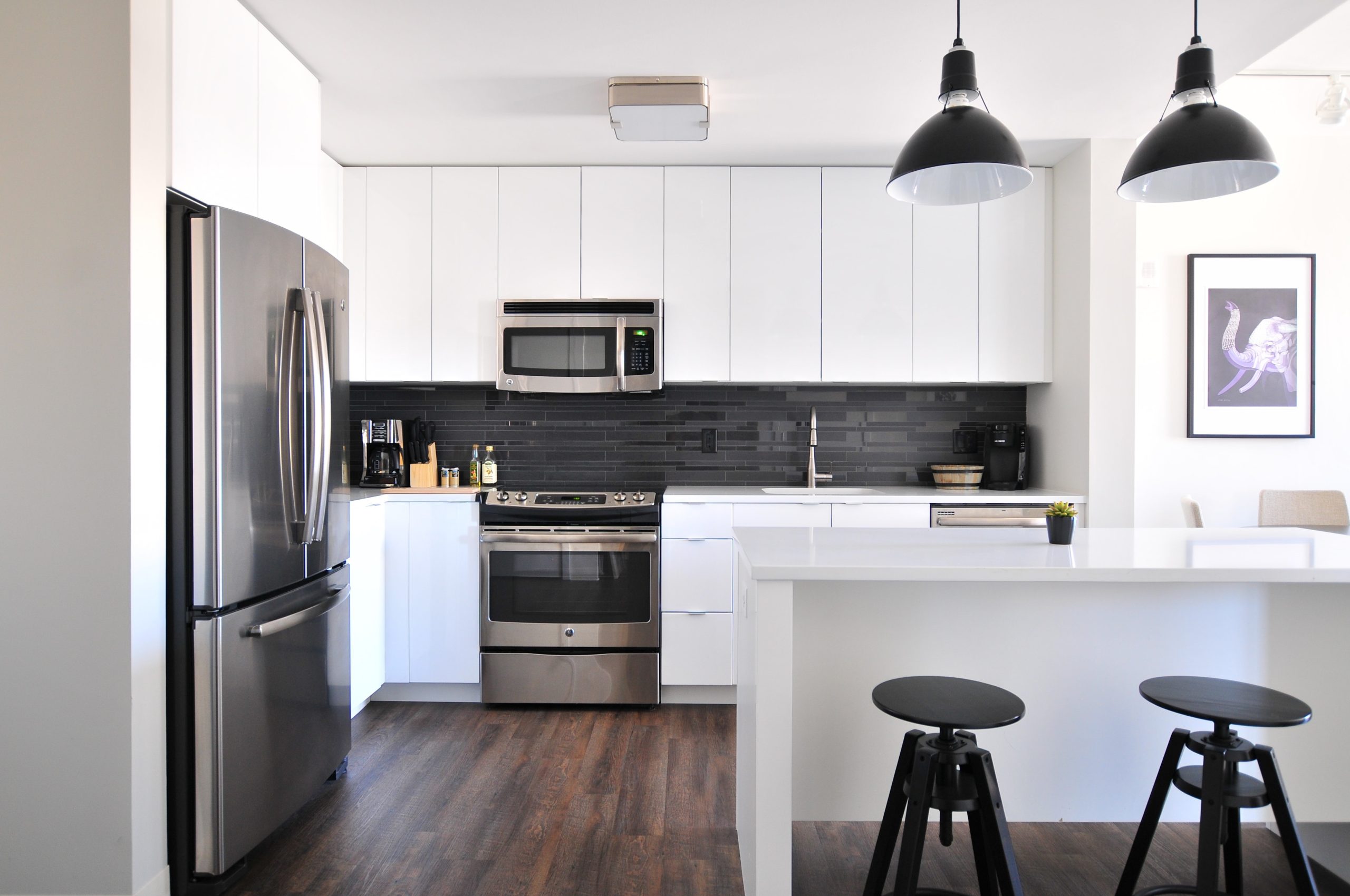 A white kitchen with black lighting and a fridge and oven 